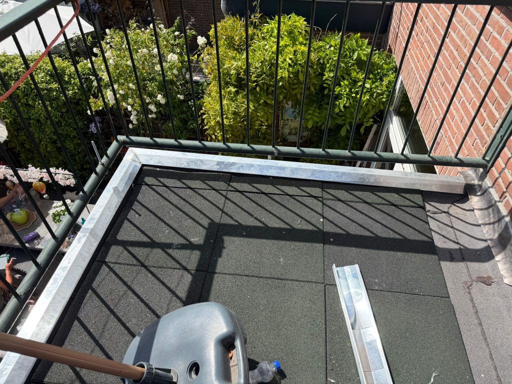 Zonovergoten balkon met groene planten en hek.